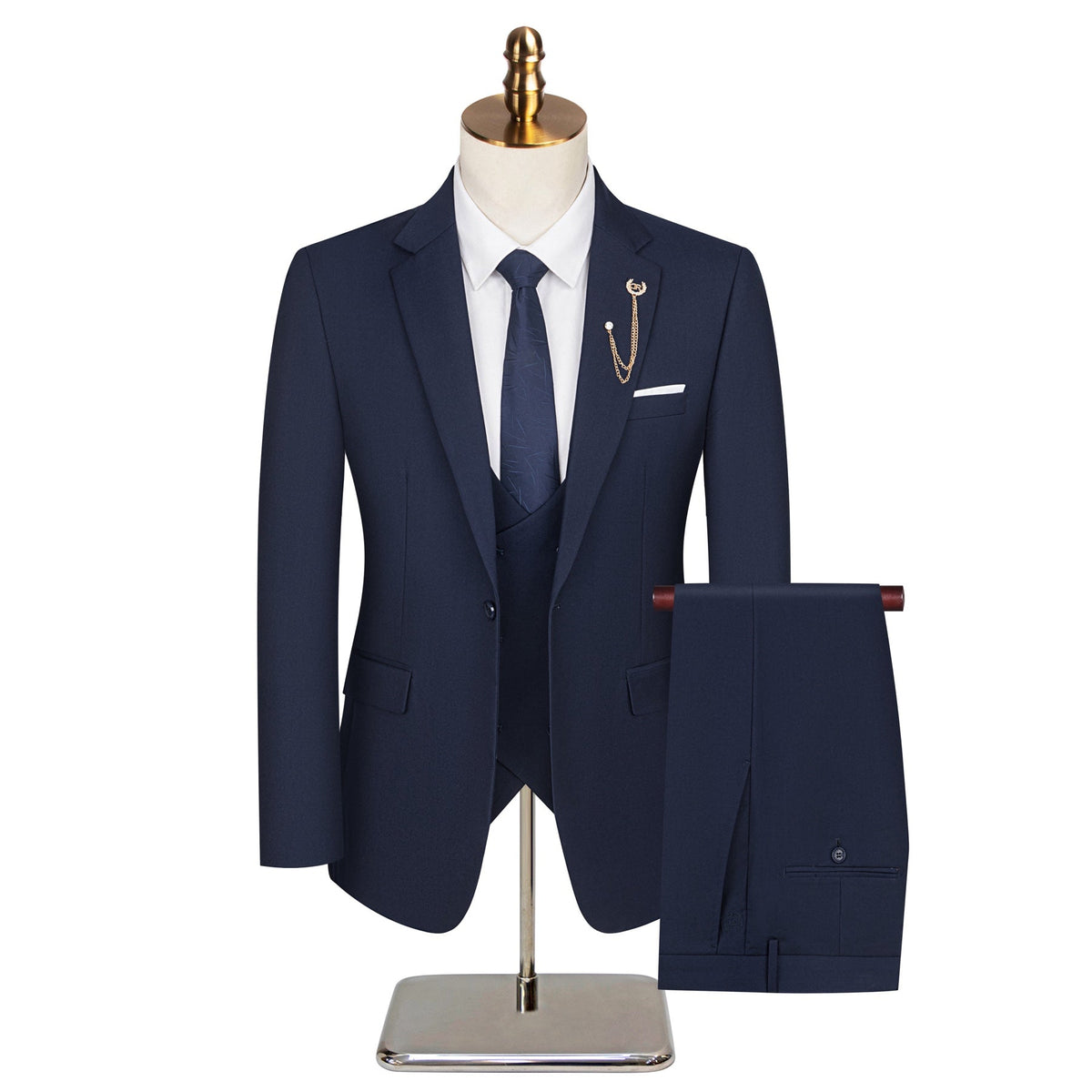 Full view of a men's navy blue three-piece suit with a white shirt, patterned tie, and gold chain lapel pin on a mannequin.