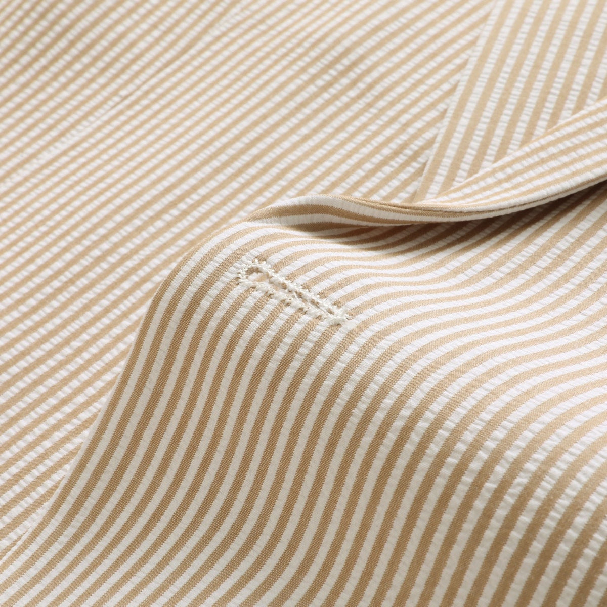 A men's beige and white striped seersucker two-piece suit, including a single-breasted jacket and matching trousers,