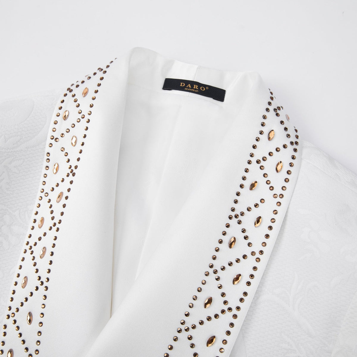 Full view of a men's white jacquard double-breasted suit with studded shawl lapels, paired with black trousers and brown