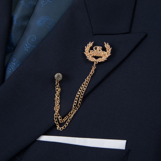 Full view of a men's navy double-breasted suit with gold buttons, a peak lapel, and a decorative brooch, paired with matching